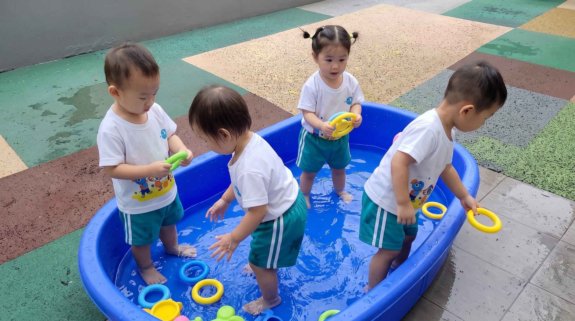 孩子们在中心的浅蓝色水盆里玩水上玩具