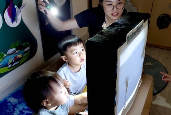 两个幼儿与老师一起看屏幕