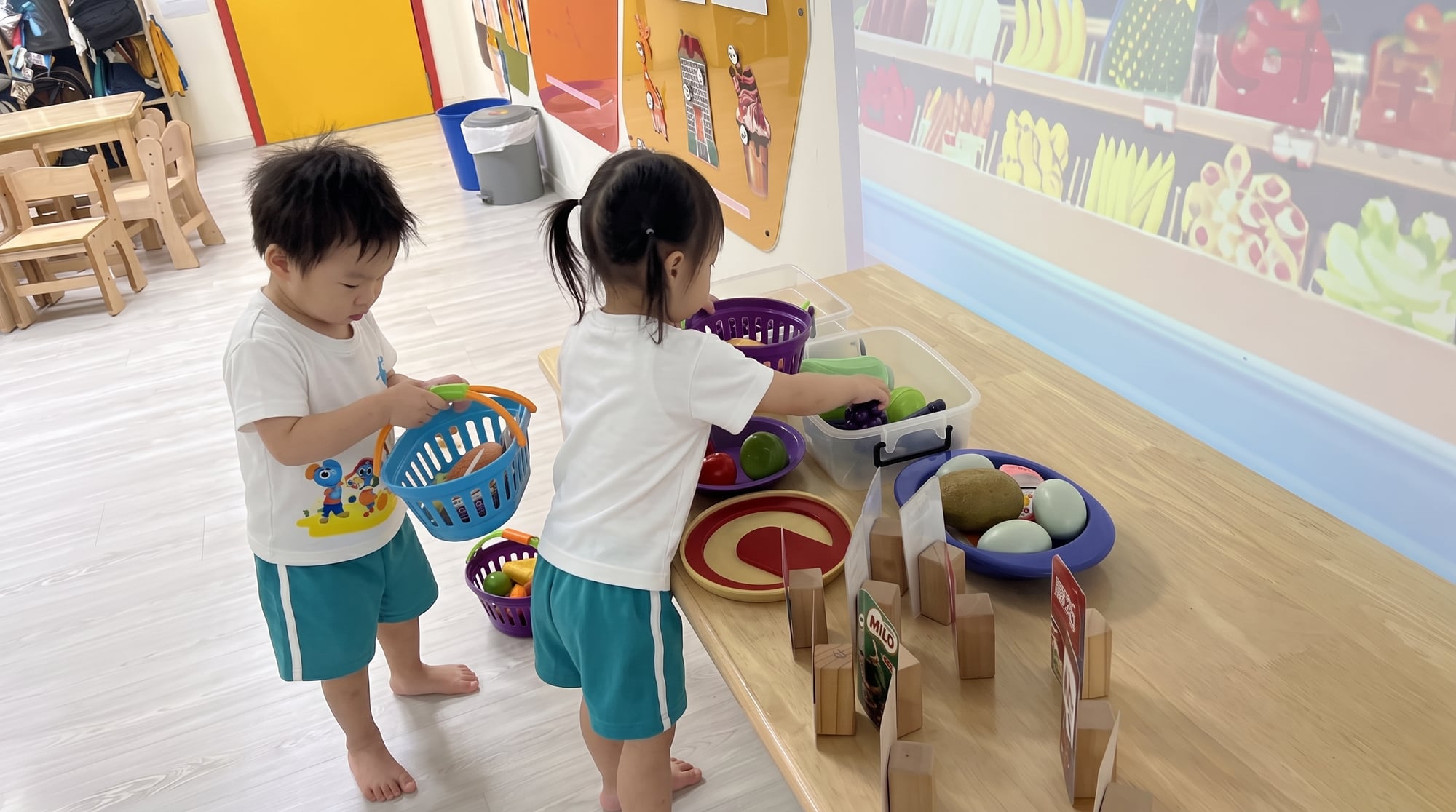 两个幼儿在玩过家家,提着篮子和玩具食物