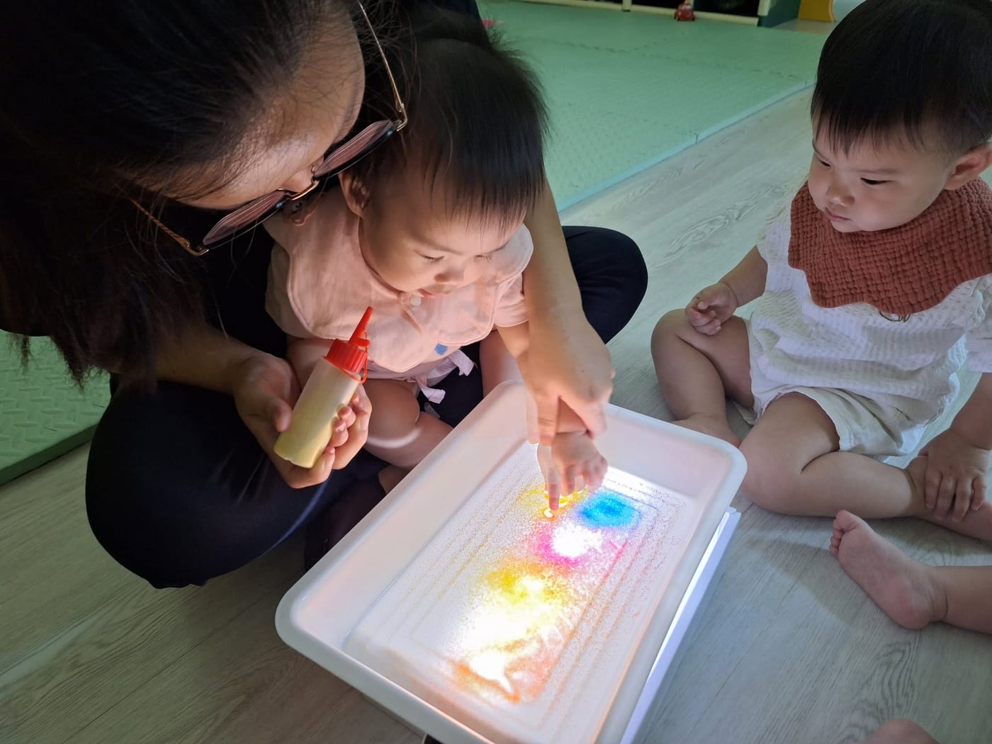 宝宝与保育员在发光托盘上探索颜色